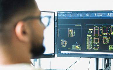 Mann schaut auf Monitor mit technischen Zeichnungen